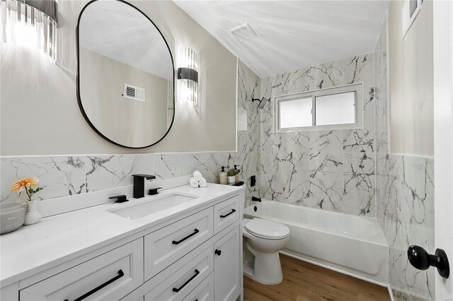 full bathroom featuring tile walls, hardwood / wood-style floors, vanity, toilet, and tiled shower / bath