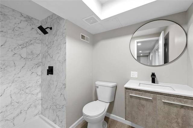 bathroom featuring vanity, toilet, wood-type flooring, and a tile shower