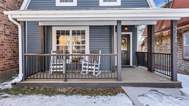 snow covered property entrance with a porch