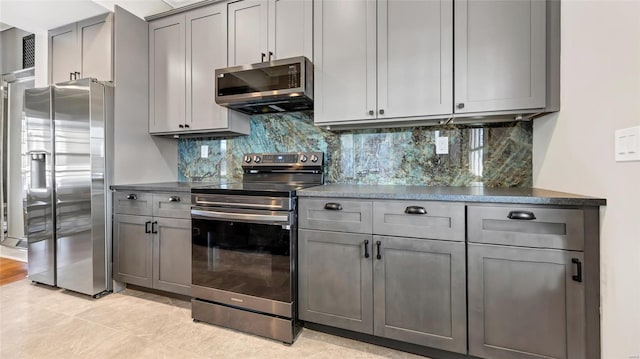 kitchen featuring light tile patterned floors, appliances with stainless steel finishes, gray cabinetry, and tasteful backsplash