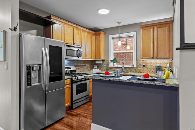 kitchen with dark wood-type flooring, appliances with stainless steel finishes, backsplash, and decorative light fixtures