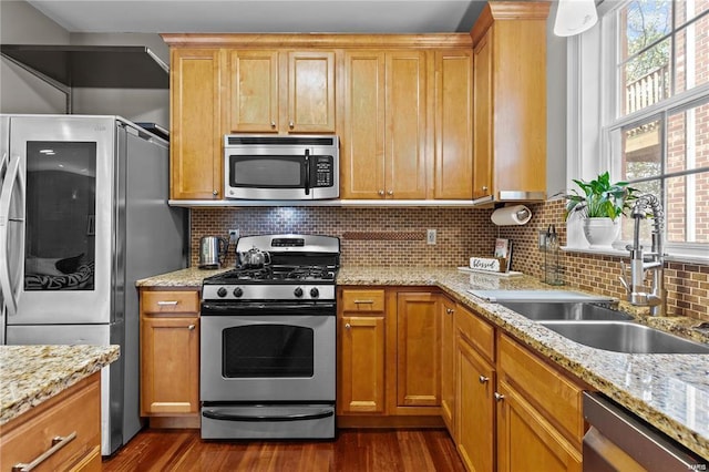 kitchen with light stone countertops, appliances with stainless steel finishes, backsplash, and sink