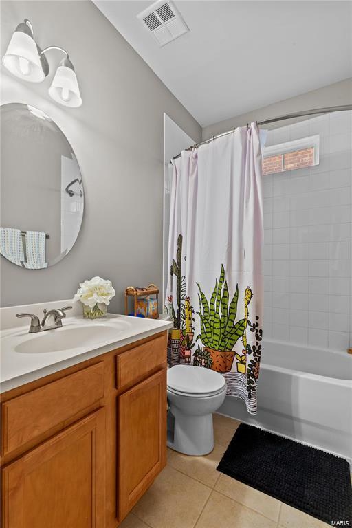 full bathroom featuring toilet, vanity, tile patterned flooring, and shower / bathtub combination with curtain