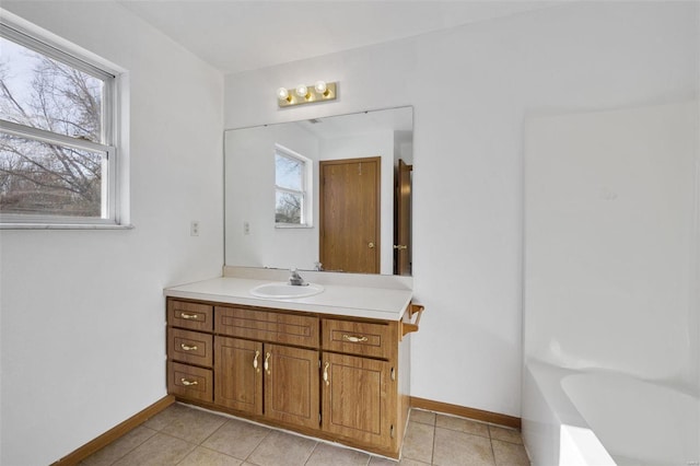 bathroom featuring a healthy amount of sunlight, tile patterned flooring, a washtub, and vanity