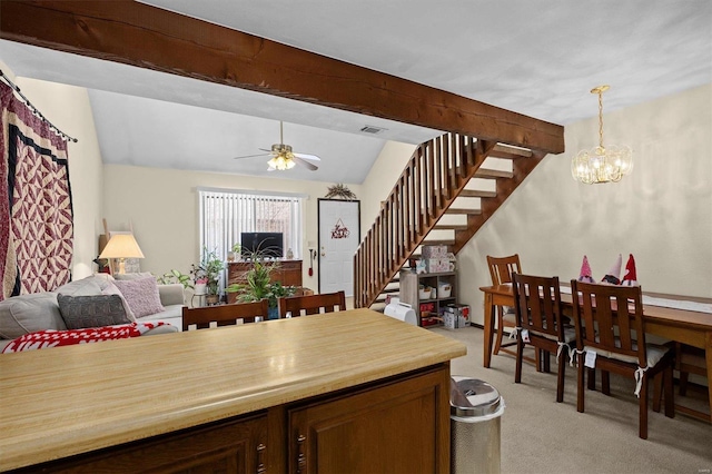 kitchen with ceiling fan with notable chandelier, light colored carpet, pendant lighting, and vaulted ceiling with beams