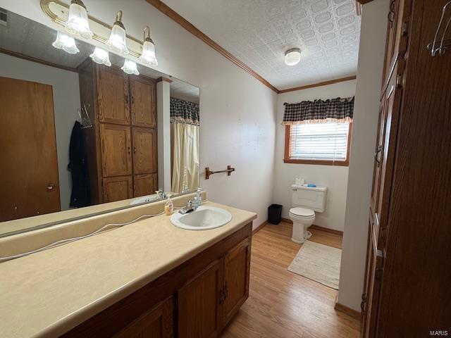 bathroom featuring a textured ceiling, wood-type flooring, vanity, toilet, and crown molding