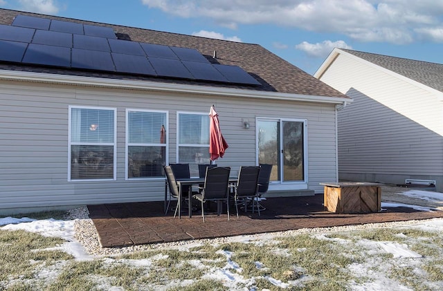 snow covered property featuring a patio and solar panels