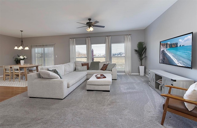 carpeted living room with ceiling fan with notable chandelier