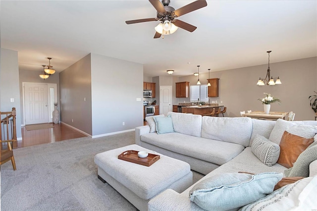 carpeted living room featuring sink and ceiling fan with notable chandelier