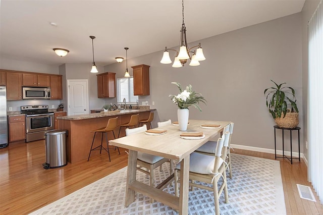 dining room featuring light hardwood / wood-style floors, sink, and an inviting chandelier