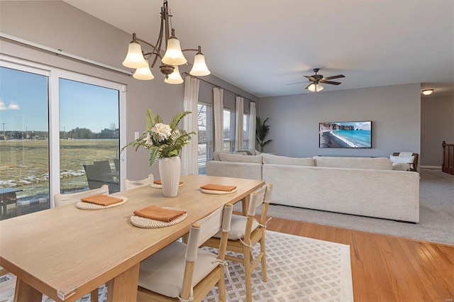 dining area featuring light hardwood / wood-style floors and ceiling fan with notable chandelier