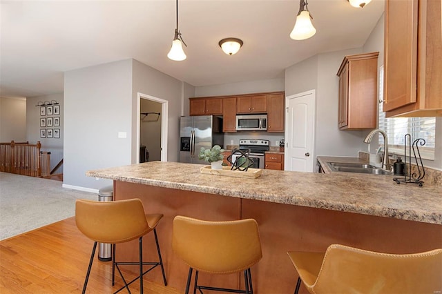 kitchen with sink, stainless steel appliances, light hardwood / wood-style flooring, and kitchen peninsula