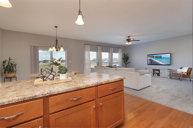 kitchen featuring plenty of natural light, ceiling fan with notable chandelier, hanging light fixtures, and light hardwood / wood-style floors