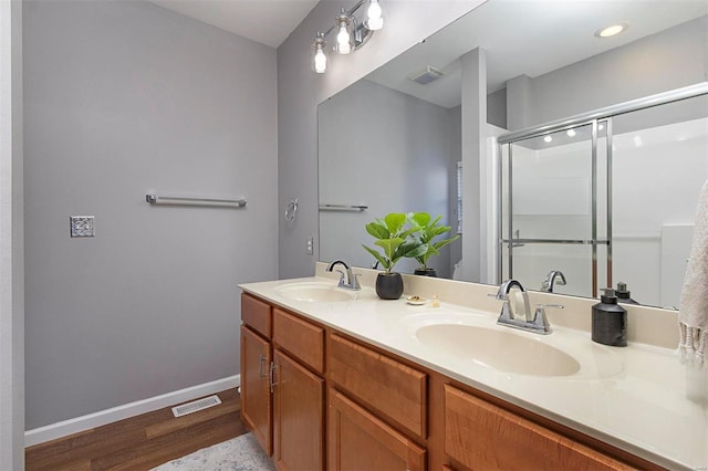 bathroom with a shower with door, hardwood / wood-style floors, and vanity