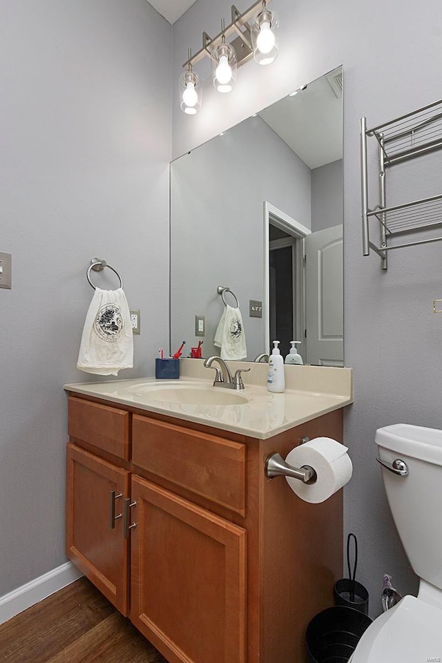 bathroom with wood-type flooring, toilet, and vanity