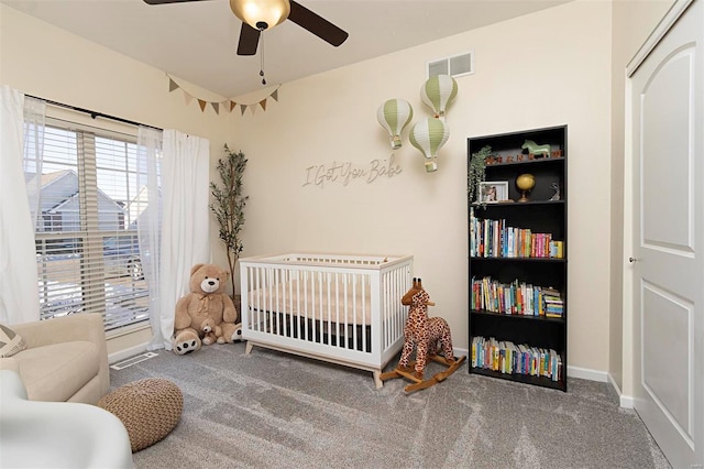 carpeted bedroom featuring ceiling fan and a nursery area