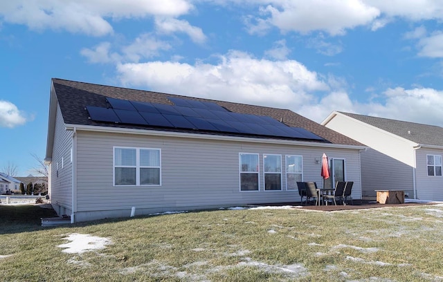 rear view of property with a patio area, a yard, and solar panels