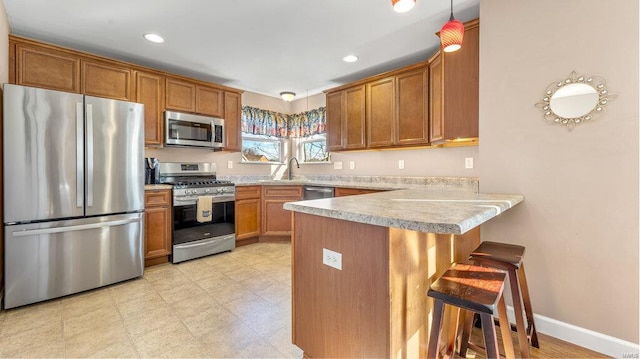 kitchen with decorative light fixtures, a kitchen breakfast bar, kitchen peninsula, and stainless steel appliances