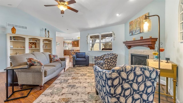 living room featuring a fireplace, wood-type flooring, ceiling fan, and vaulted ceiling