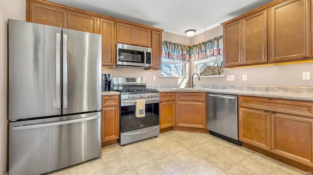 kitchen with sink, light stone countertops, and stainless steel appliances