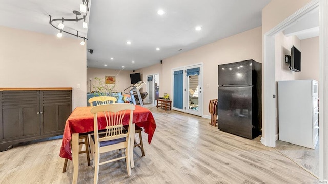 dining area with light hardwood / wood-style flooring and track lighting