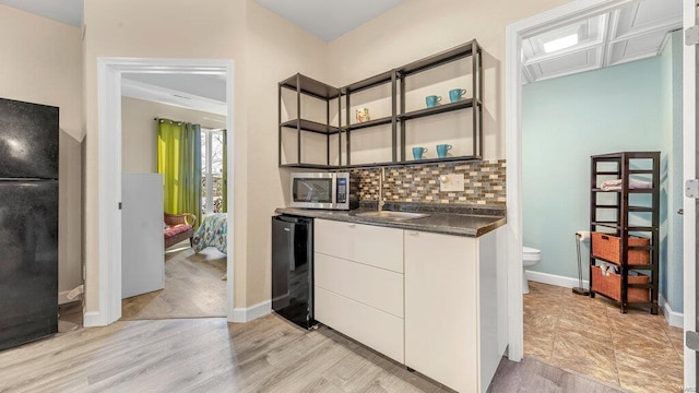 kitchen featuring white cabinetry, sink, light wood-type flooring, black fridge, and wine cooler