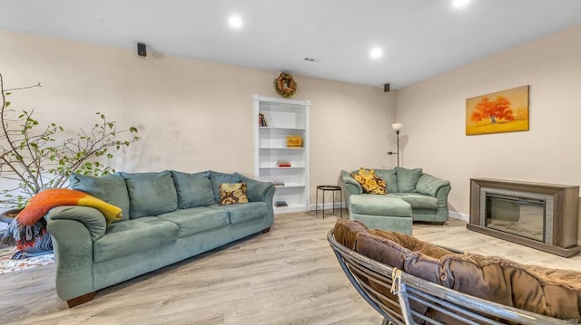 living room with built in shelves and light hardwood / wood-style floors