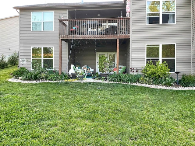 rear view of property with a balcony and a lawn