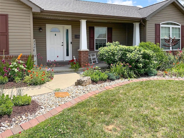 entrance to property featuring covered porch and a lawn