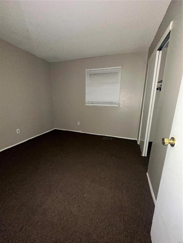 spare room featuring dark carpet