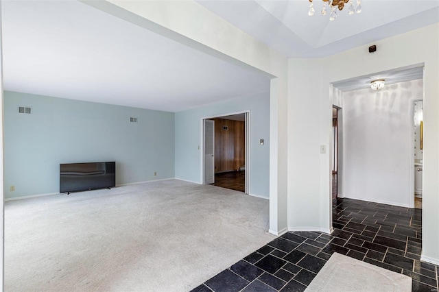 unfurnished living room with a chandelier and dark colored carpet