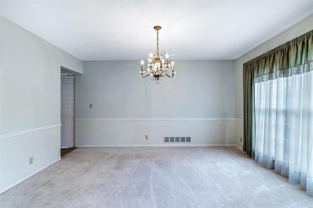 carpeted empty room featuring a chandelier