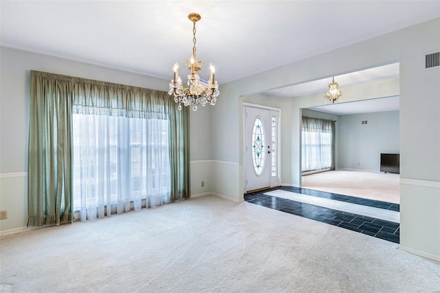 foyer entrance featuring a notable chandelier and dark colored carpet