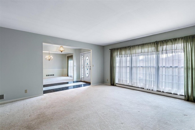 unfurnished living room featuring carpet, a baseboard heating unit, and an inviting chandelier