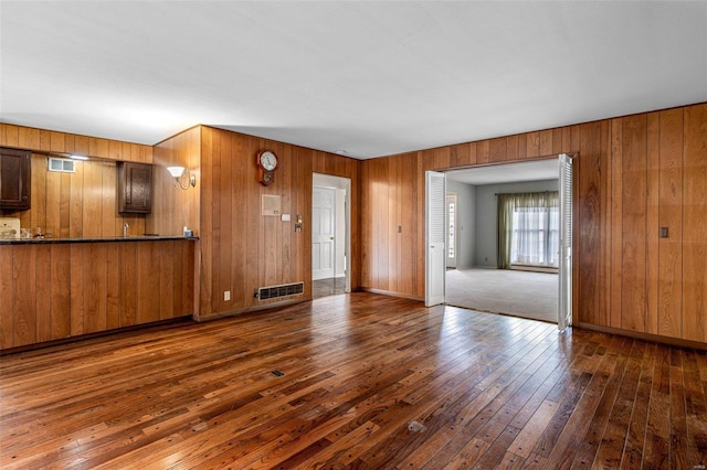 unfurnished living room featuring wooden walls and dark hardwood / wood-style flooring