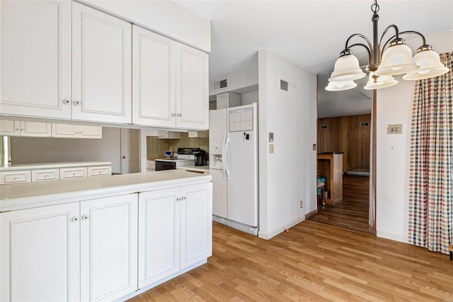 kitchen featuring white cabinetry, white refrigerator with ice dispenser, electric range oven, and decorative light fixtures