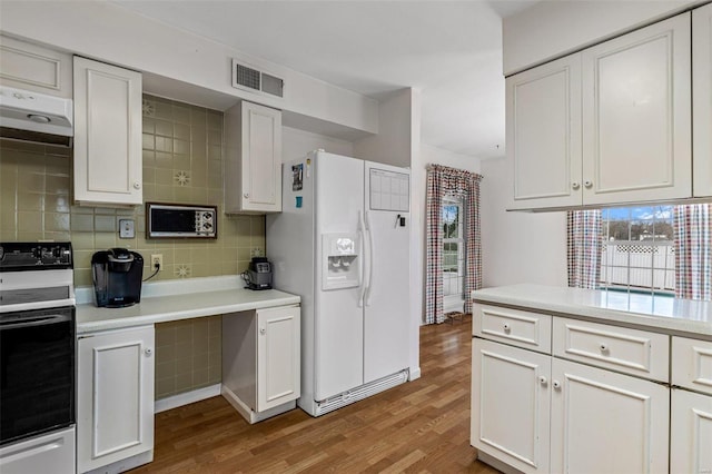 kitchen featuring hardwood / wood-style flooring, backsplash, range with electric stovetop, white refrigerator with ice dispenser, and white cabinets