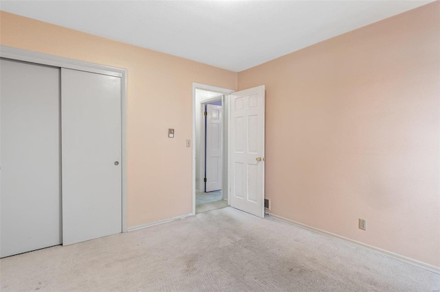 unfurnished bedroom featuring light colored carpet and a closet