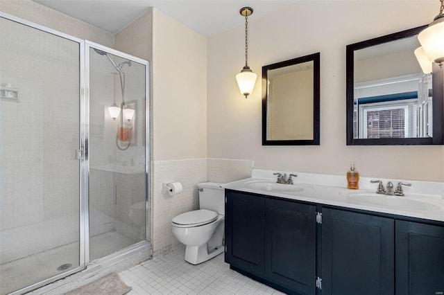 bathroom with a shower with shower door, tile walls, vanity, toilet, and tile patterned floors