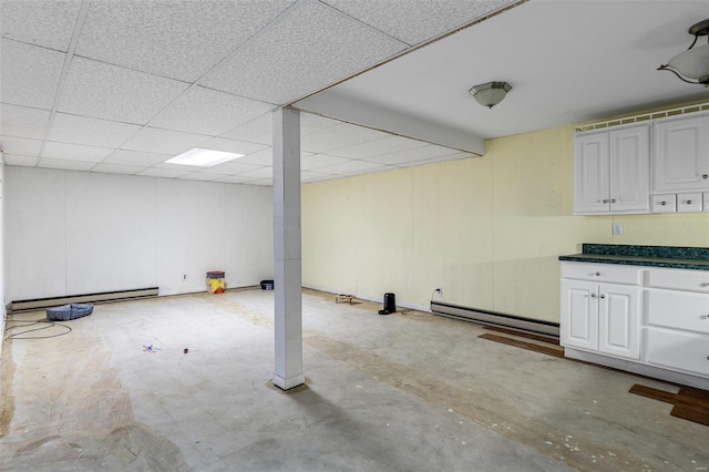 basement featuring a drop ceiling and baseboard heating