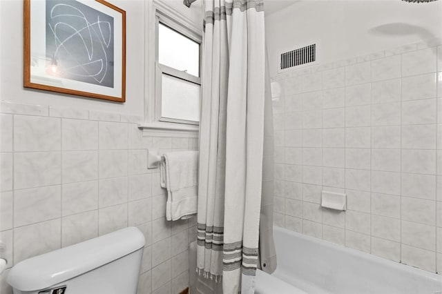 bathroom with tile walls, toilet, and shower / bathtub combination with curtain