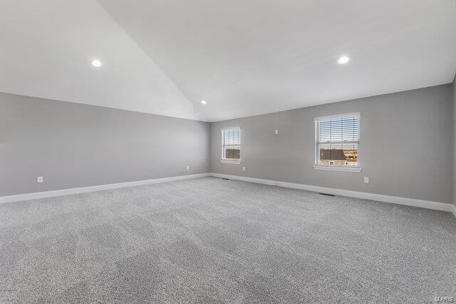 spare room with carpet flooring and vaulted ceiling