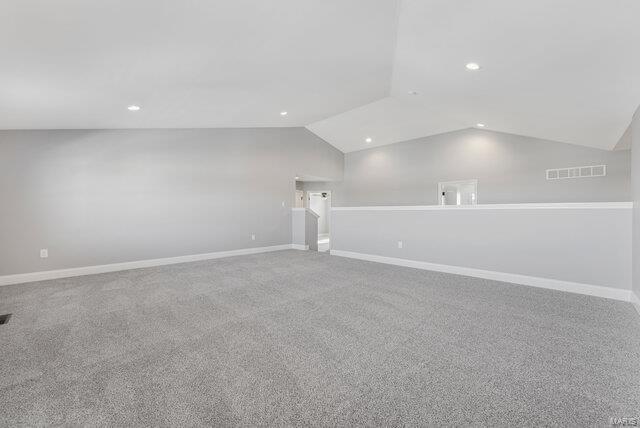 carpeted empty room featuring lofted ceiling