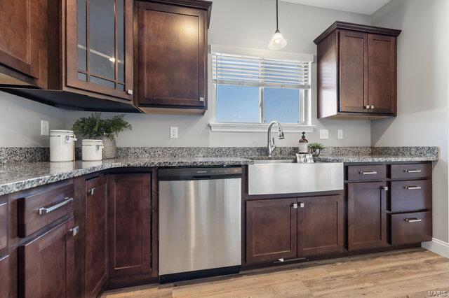 kitchen featuring light stone countertops, sink, stainless steel dishwasher, and light hardwood / wood-style flooring