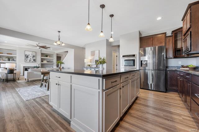 kitchen featuring built in shelves, dark brown cabinetry, a center island, appliances with stainless steel finishes, and light hardwood / wood-style floors