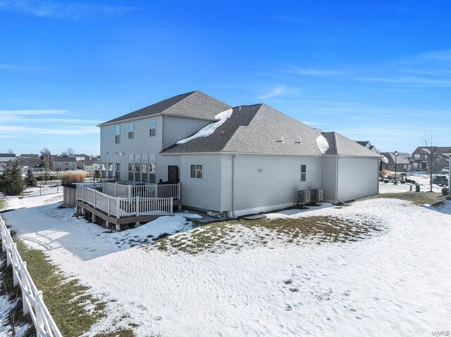 snow covered house featuring cooling unit and a deck