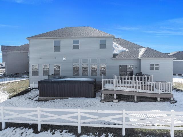 snow covered house with a wooden deck and a hot tub