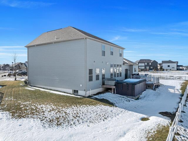 snow covered house featuring a hot tub and a deck