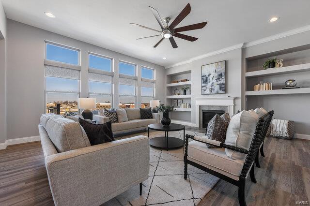 living room with hardwood / wood-style floors, a wealth of natural light, built in features, and ceiling fan