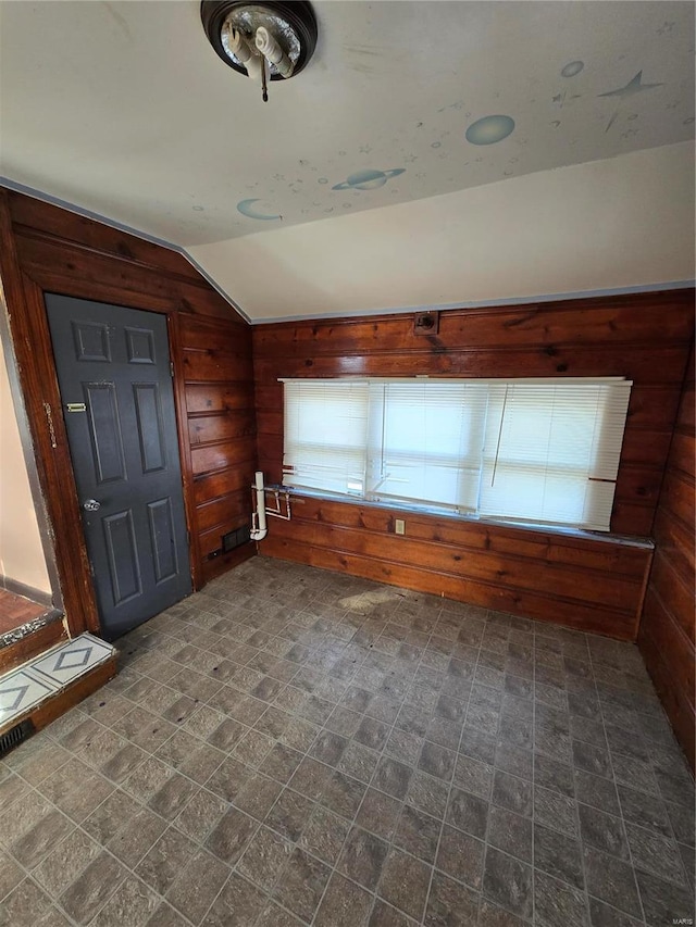 foyer entrance featuring vaulted ceiling and wooden walls